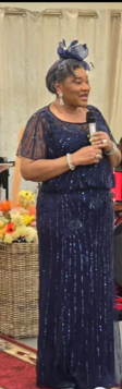 June Ajuwa Anison speaking at a gathering with a microphone
